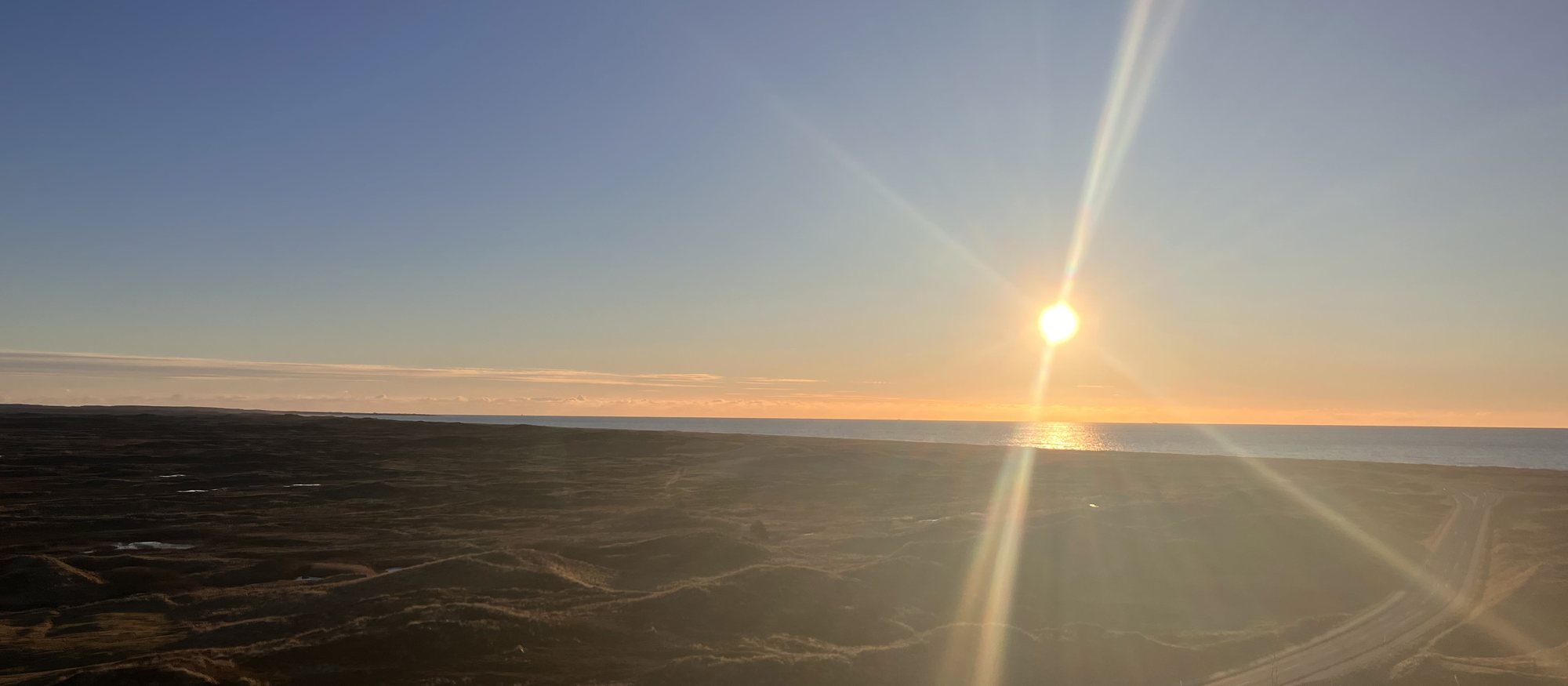 Lavtst&aring;ende sol over klitheden i Thy med Vesterhavet i horisonten